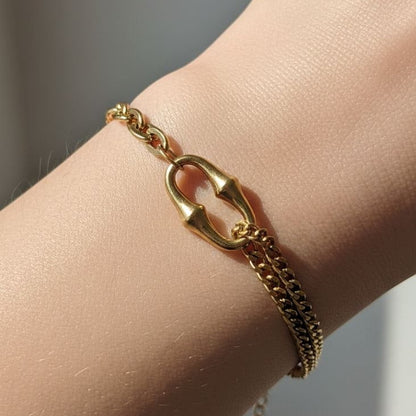 A gold-toned chain bracelet with a distinctive interlocking double-oval clasp, shown worn on a person's wrist.